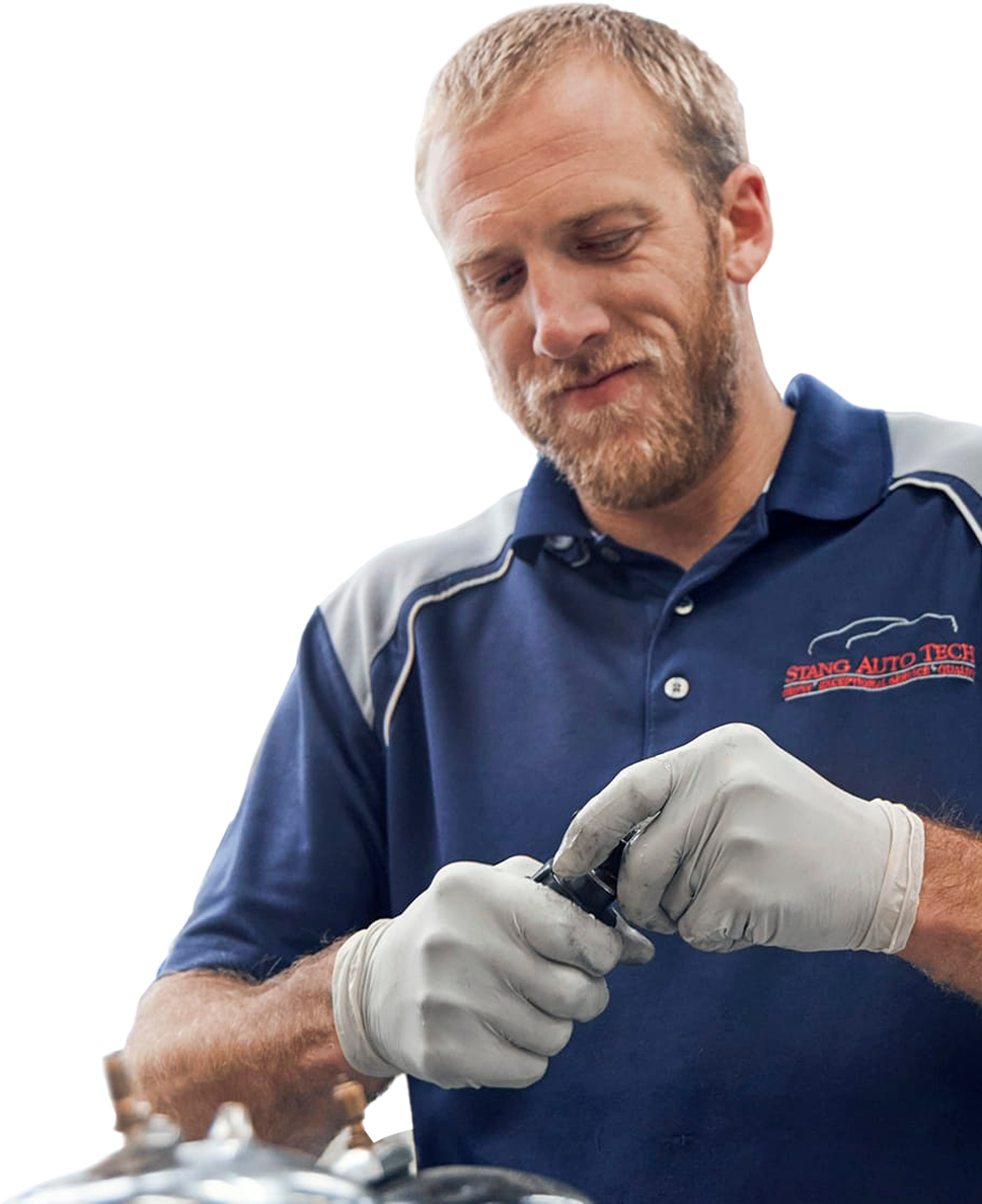 A mechanic wearing gloves, working on a car part. | Stang Auto Tech