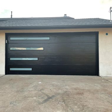 Black modern garage door with narrow horizontal windows on a beige house exterior