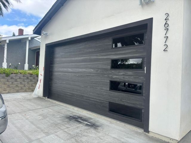 White house exterior with a dark gray garage door and small horizontal windows.