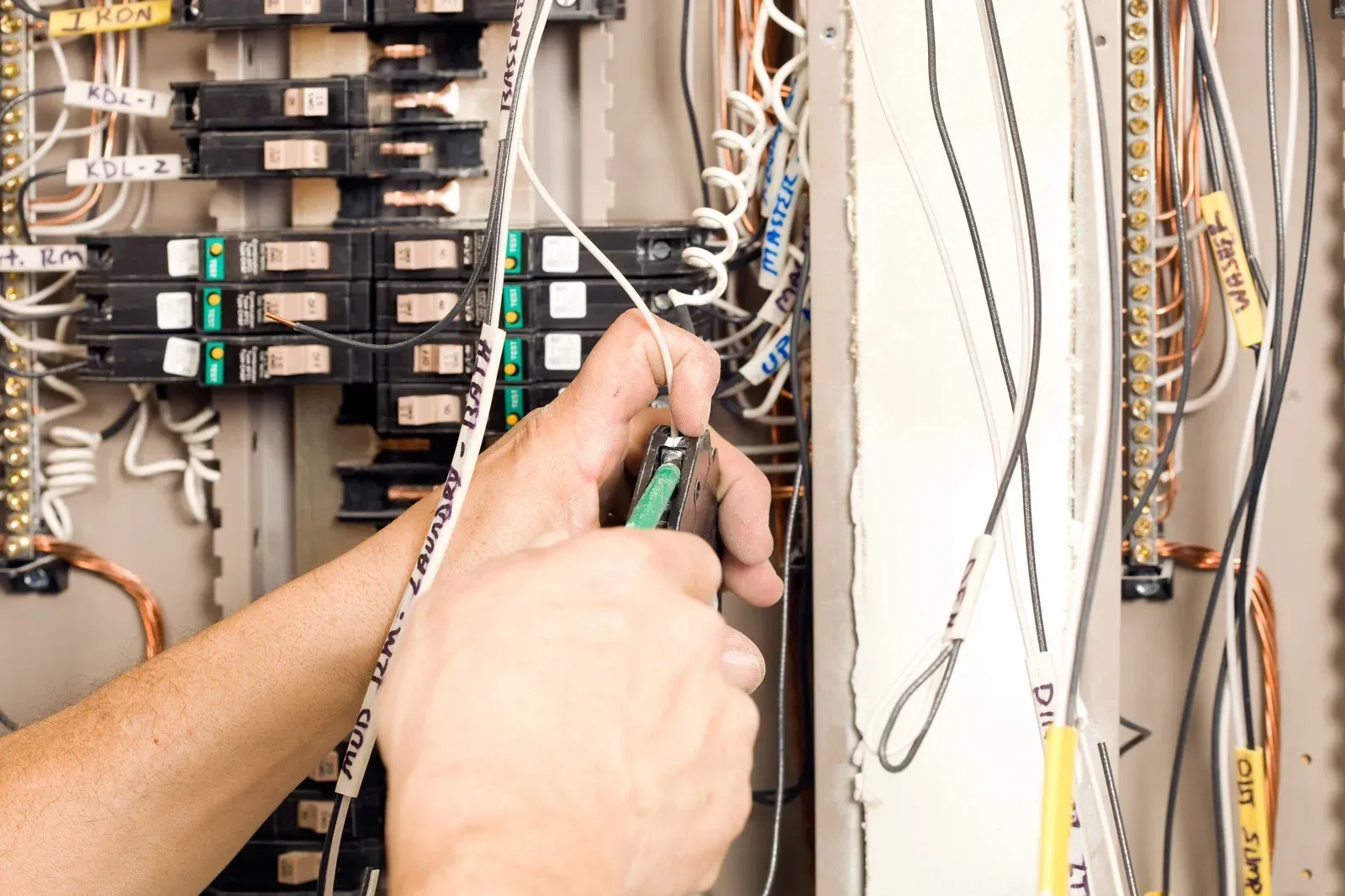 A person is working on an electrical box with a screwdriver.