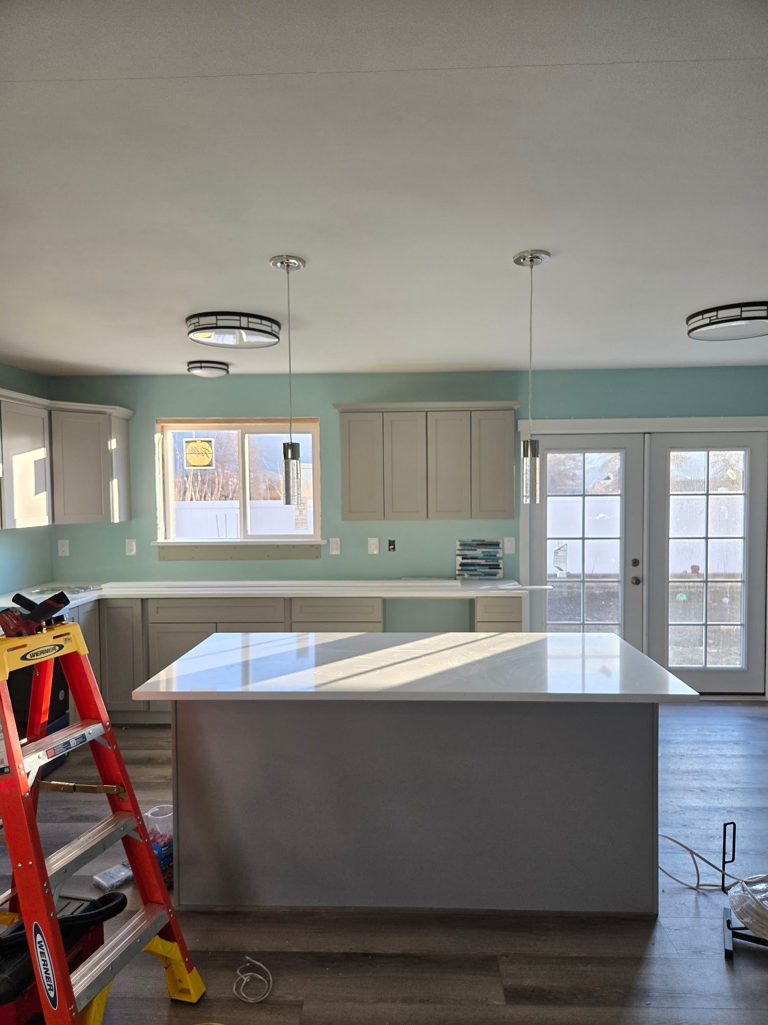 A kitchen under construction with a large island and a ladder.