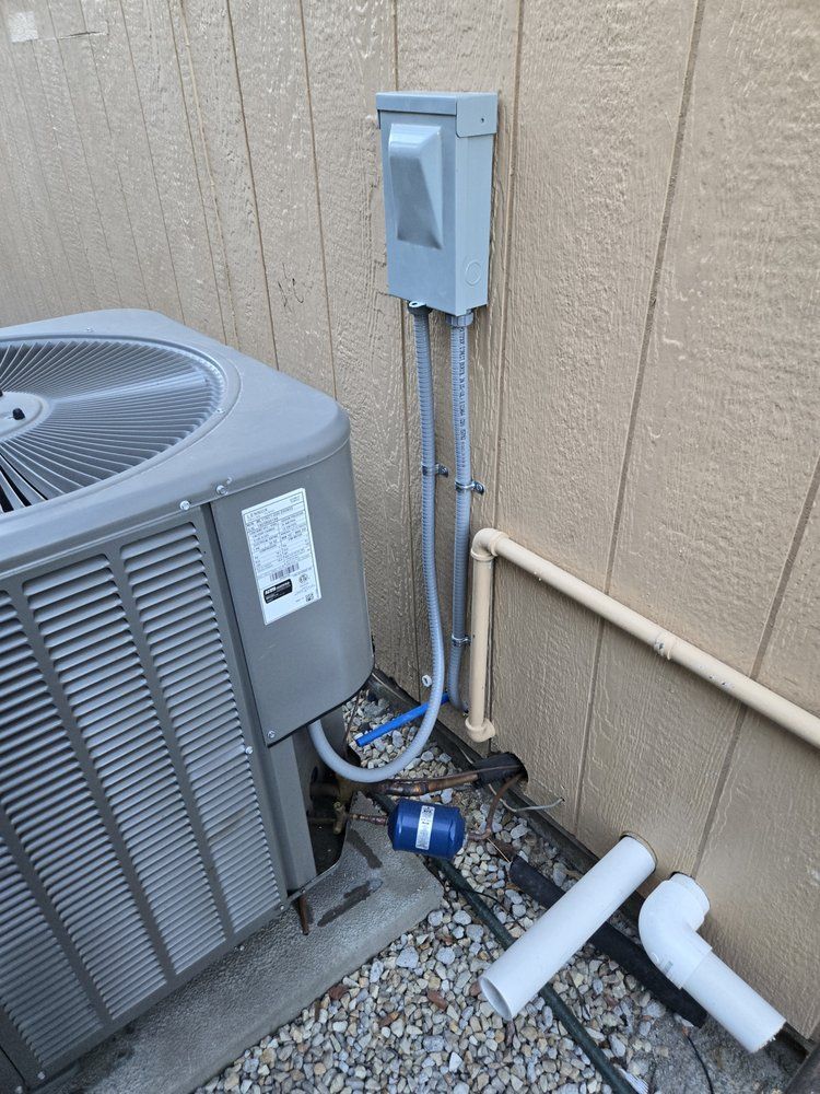 A gray air conditioner is sitting next to a wall.