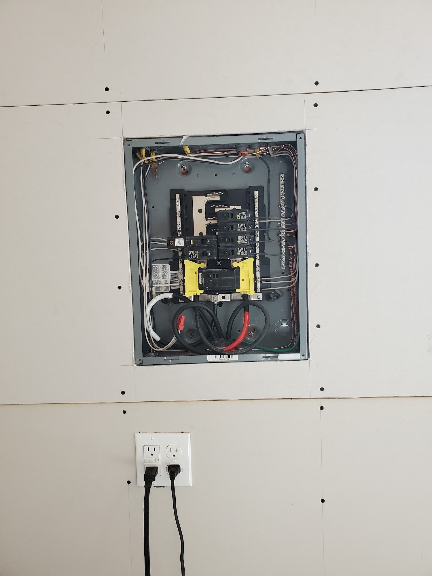 A electrical box is sitting on a wall next to a socket.