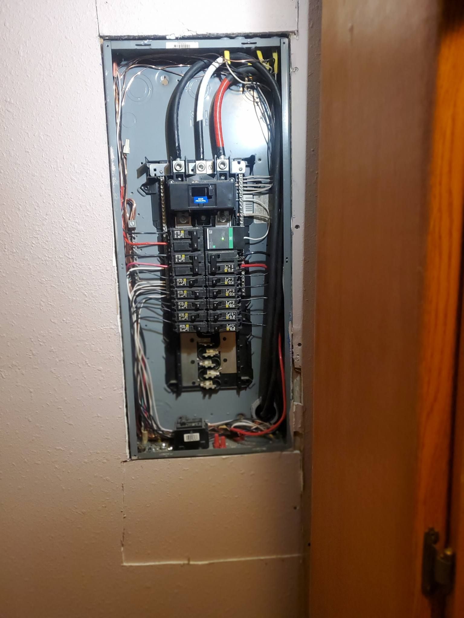 A electrical panel is sitting on a wall next to a door.