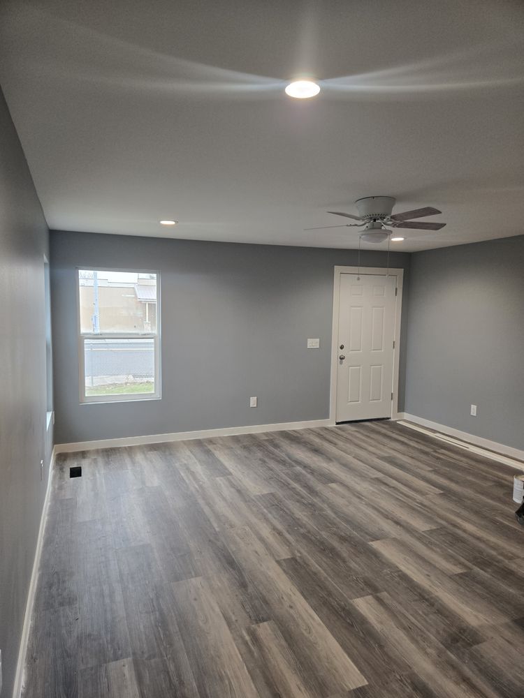 An empty living room with hardwood floors and a ceiling fan.
