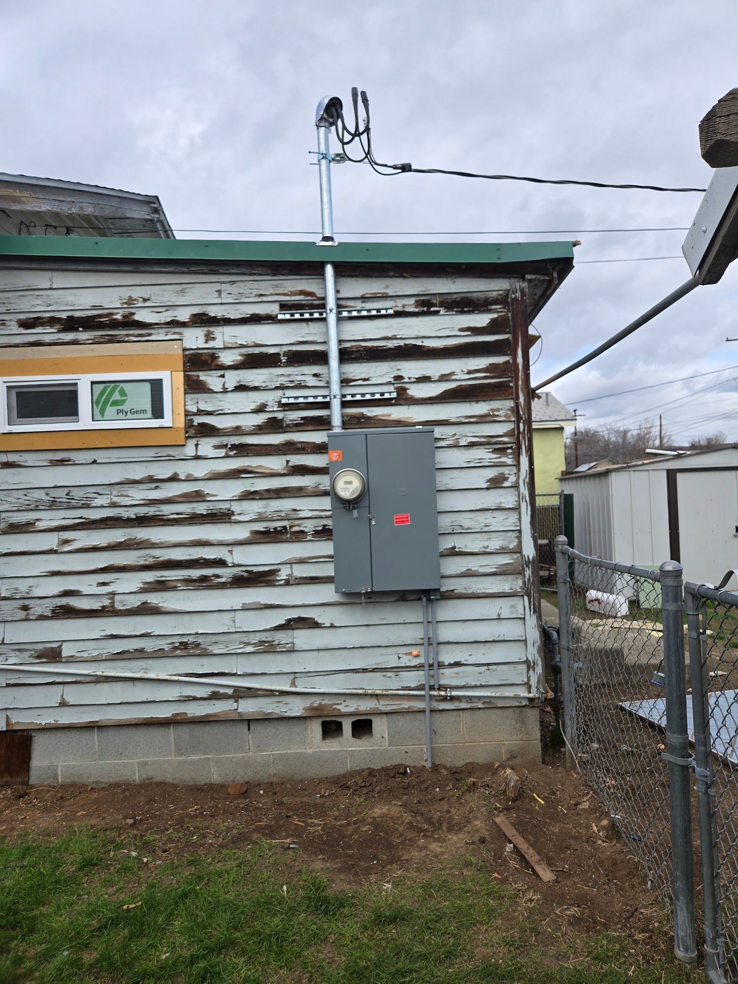 A house with a fence and a box on the side of it.