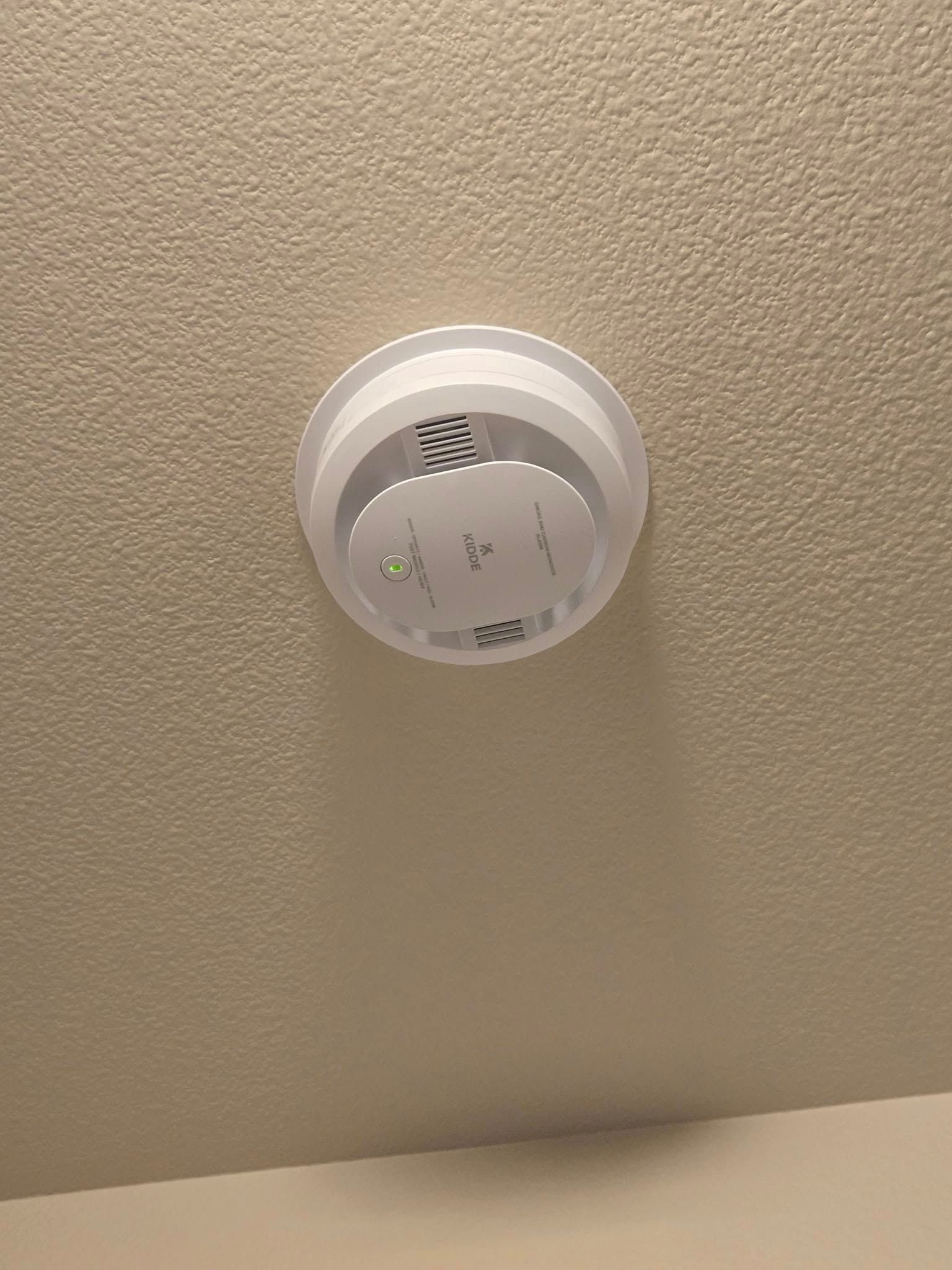 A smoke detector is hanging from the ceiling of a room.
