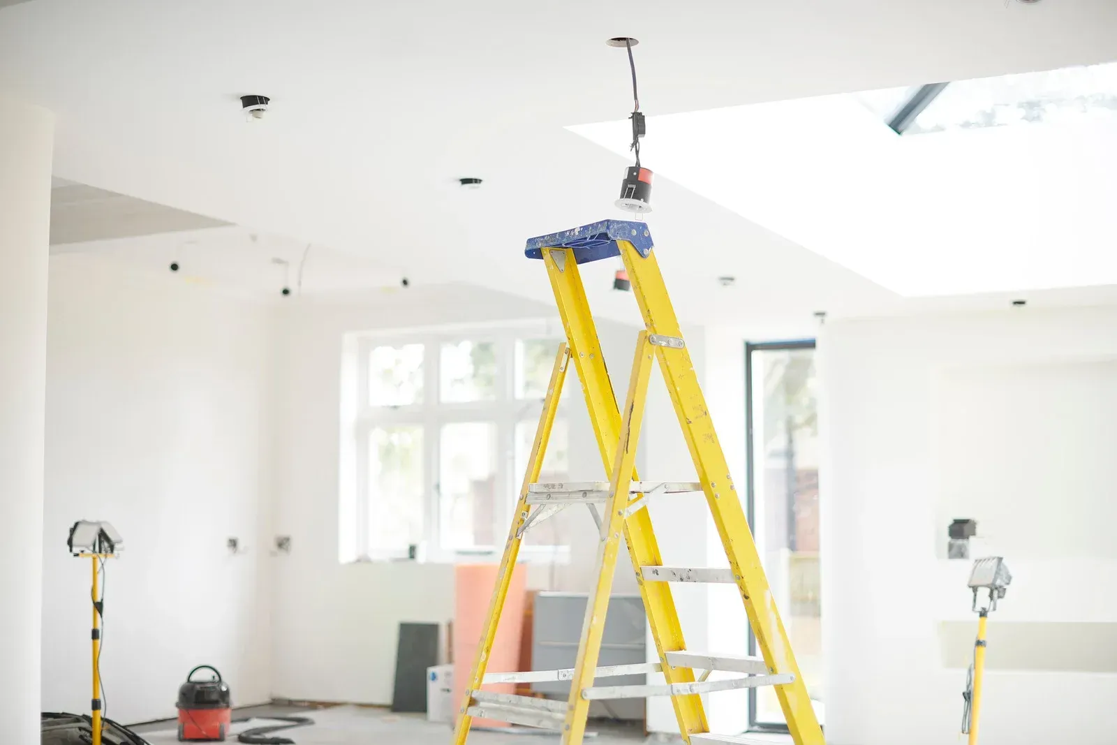 A yellow ladder is sitting in an empty room.
