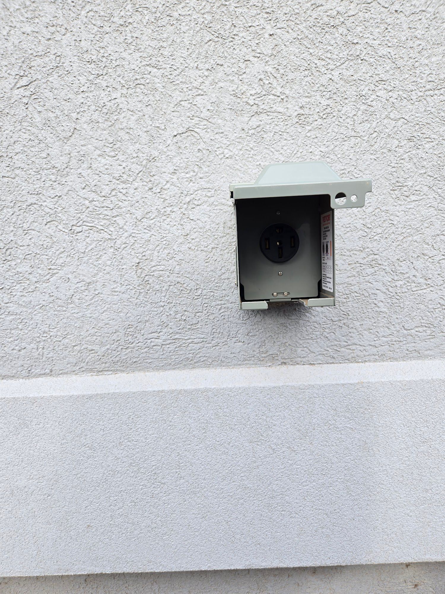 A gray wall with a box on it that looks like a birdhouse.