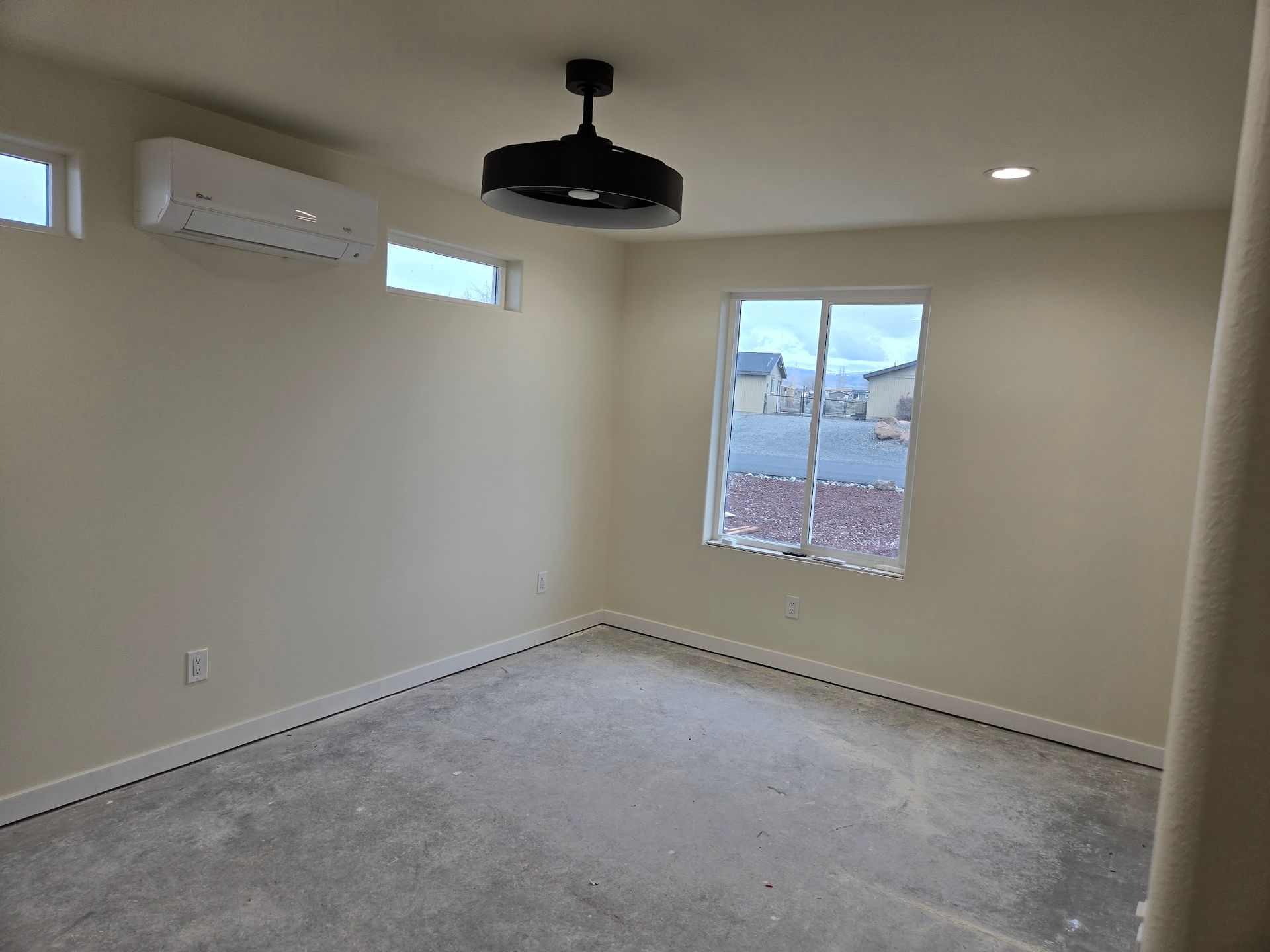 An empty room with a ceiling fan and a window.