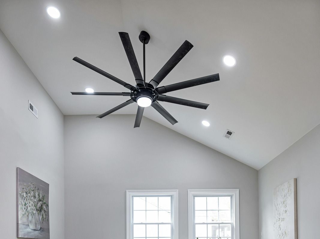 A ceiling fan is hanging from the ceiling of a room with two windows.