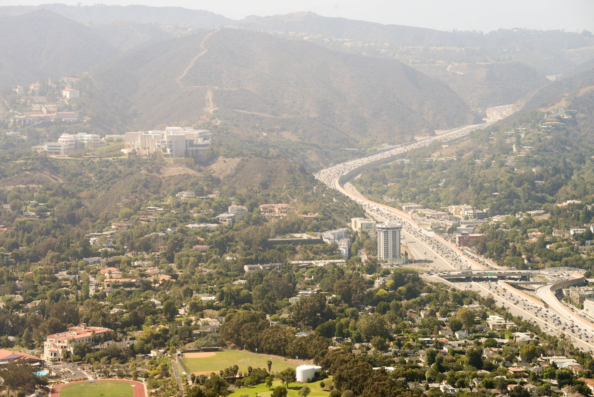 an aerial view of a highway going through a city surrounded by mountains .