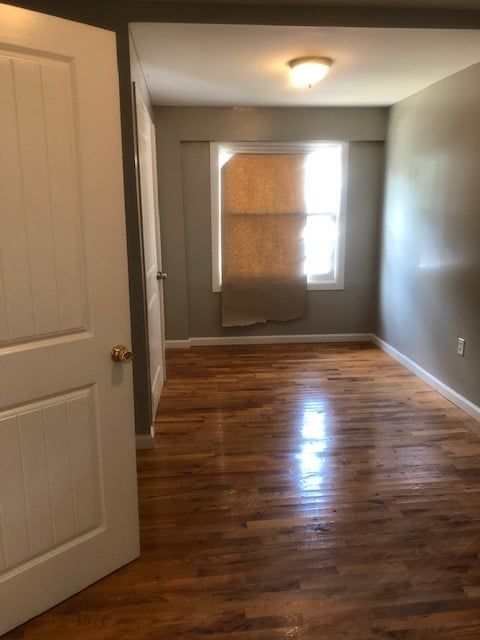 An empty room with hardwood floors and a window