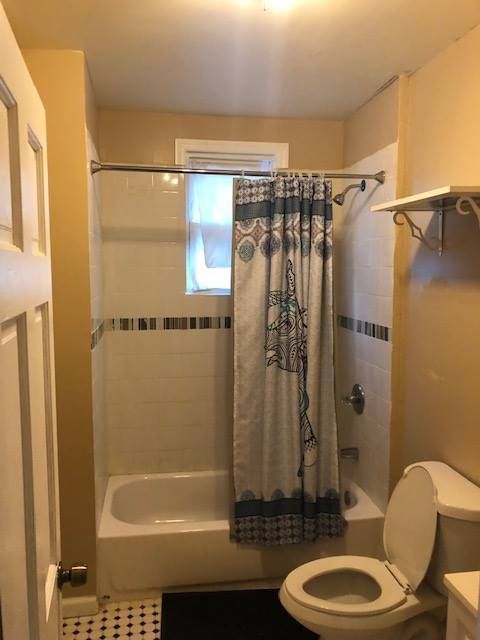 A bathroom with a toilet a tub and a shower curtain