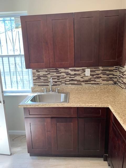 A kitchen with a sink , cabinets and granite counter tops.