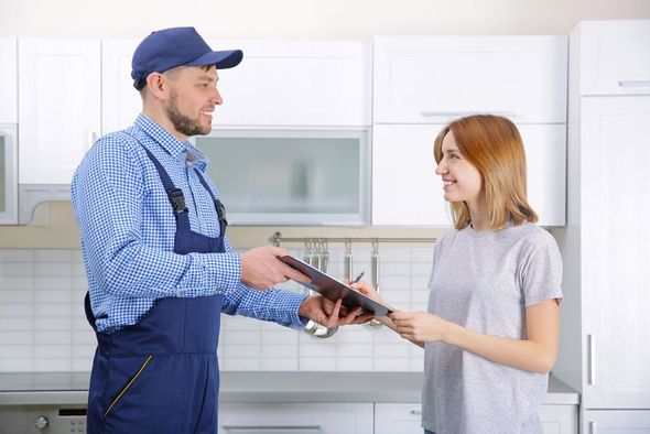 A repair technician is showing a customer information on a clipboard. They are both smiling.