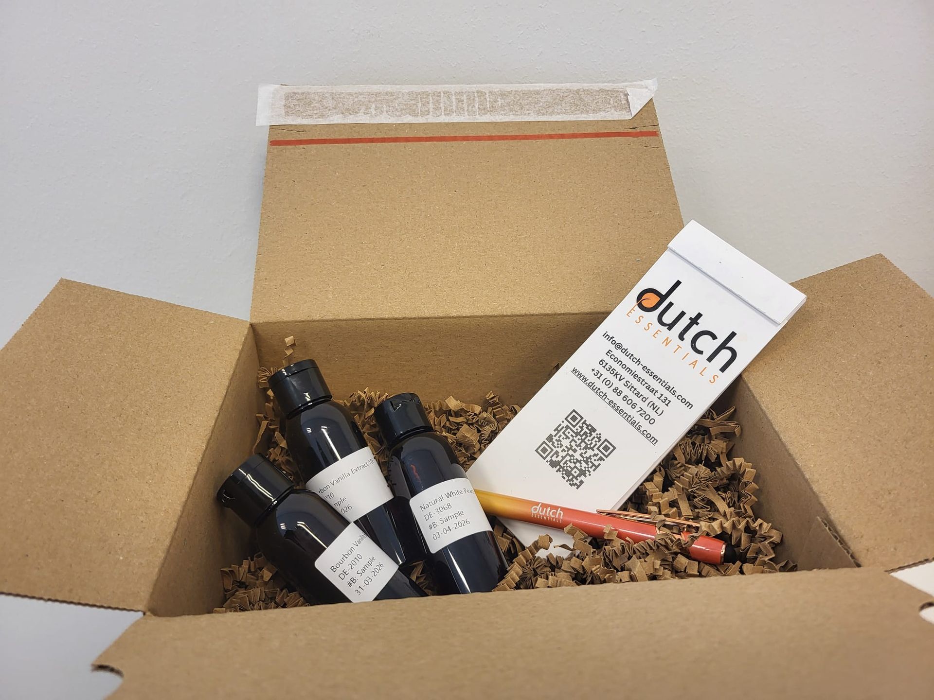 A small glass sample bottle of premium Bourbon vanilla extract in a sample box.