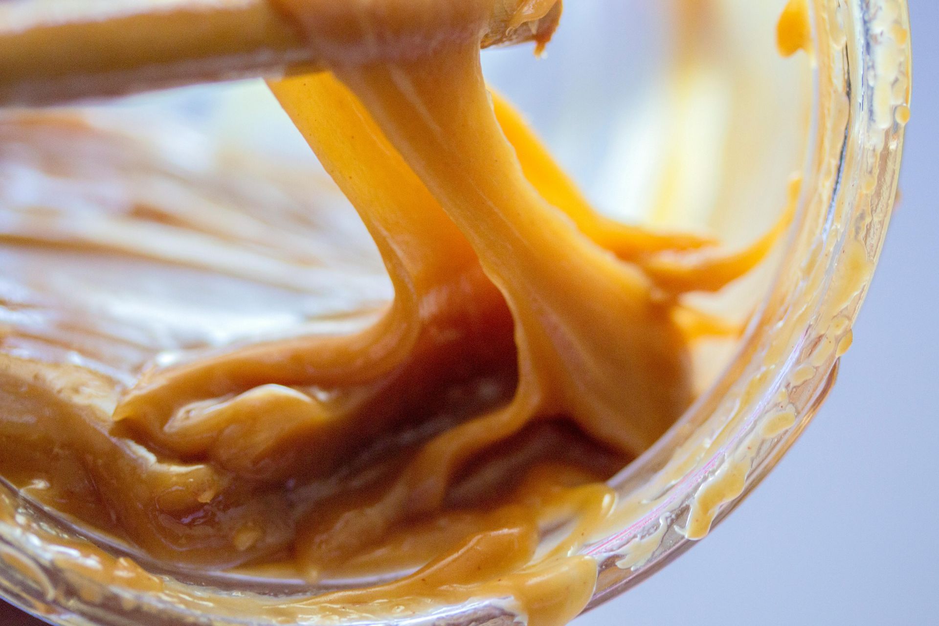 A close up of a jar of peanut butter with a spoon sticking out of it.