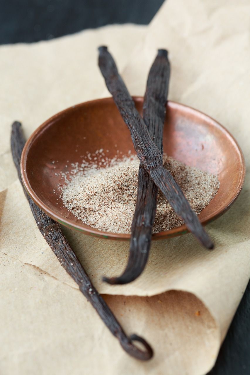 Three vanilla beans in a bowl of sugar