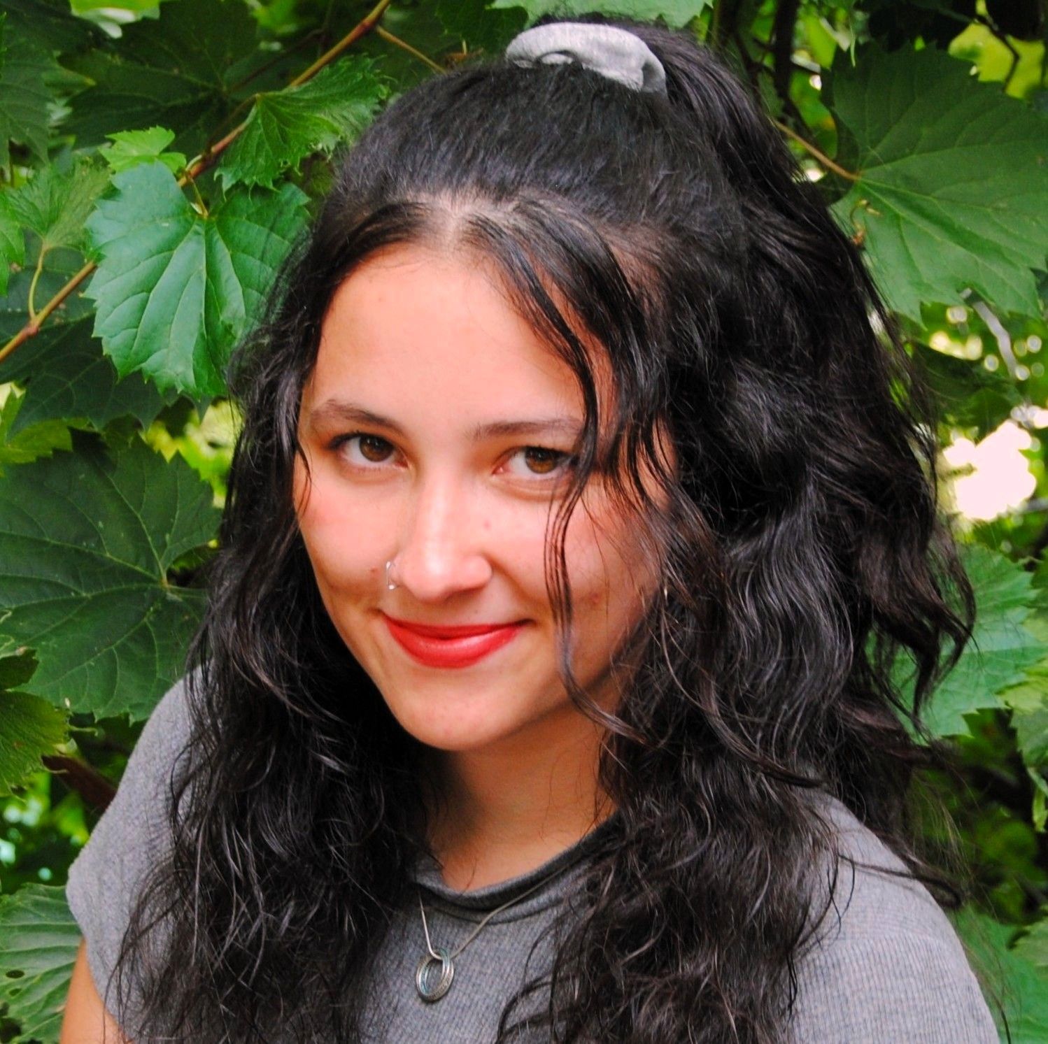 A woman is sitting at a desk with a laptop and a vase of flowers.