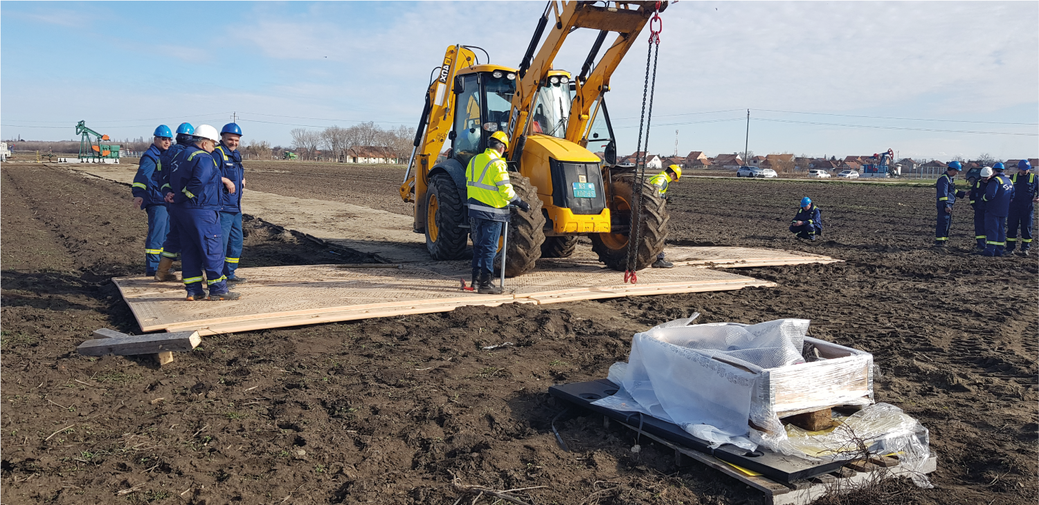 Un grupo de trabajadores de la construcción está de pie alrededor de un tractor en un campo fangoso.