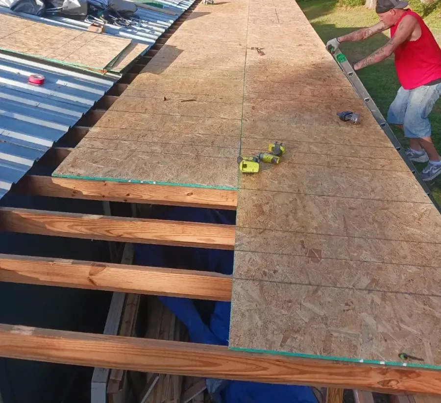 A man in a red shirt is working on a roof.