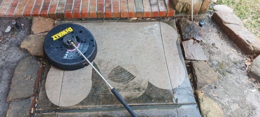 A pressure washer is being used to clean a brick walkway.