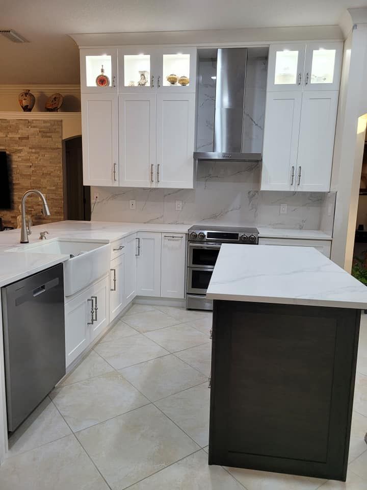 Modern kitchen with white cabinets, a dark gray island, stainless steel appliances, and a white countertop.