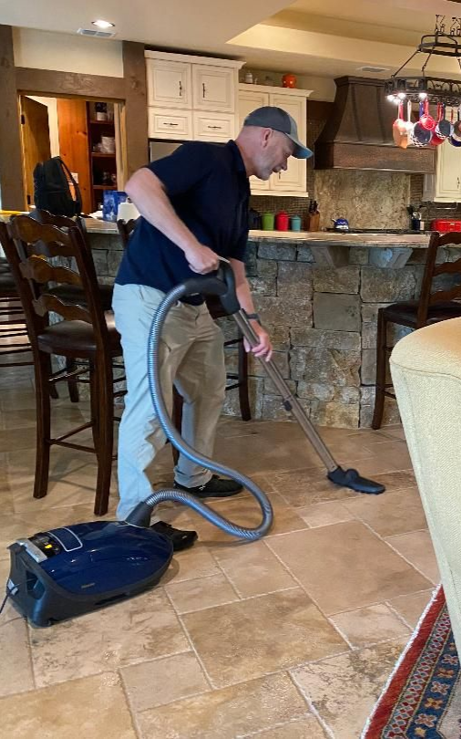 A man is using a vacuum cleaner to clean a hallway.