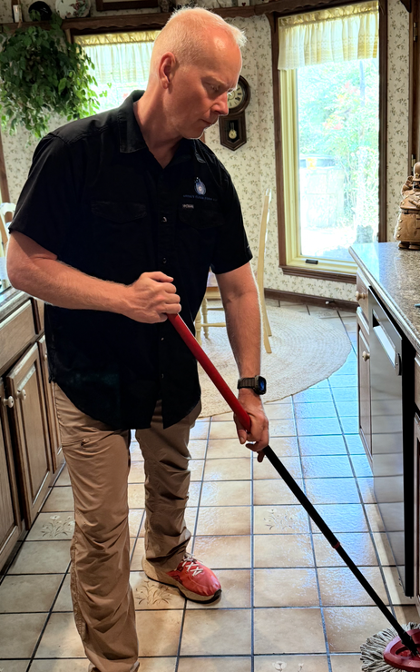 A man is using a vacuum cleaner to clean a hallway.