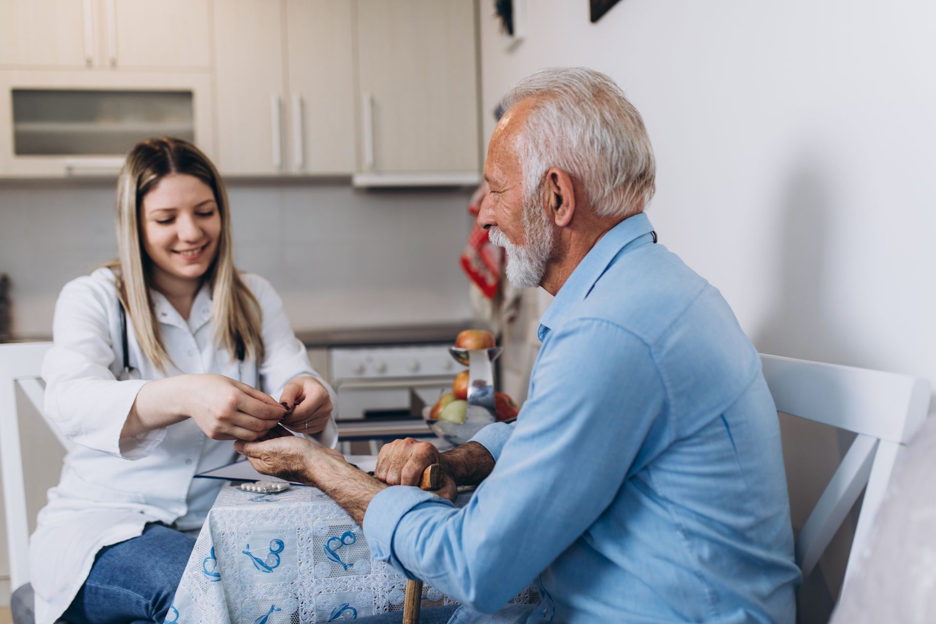 A healthcare worker in a white coat checks an older person's wrist indoors.
