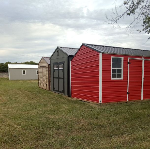 A row of sheds are lined up in a grassy field