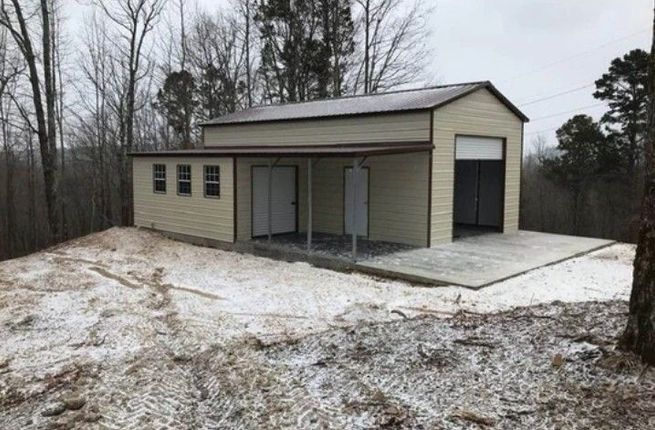 A garage with a porch is sitting on top of a snowy hill.