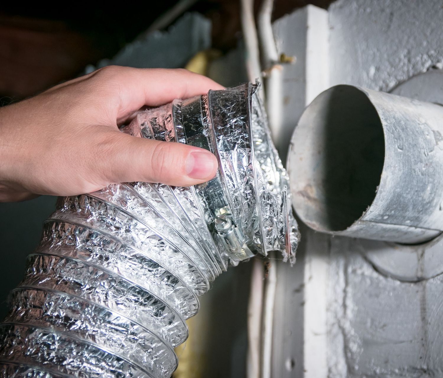 Flexible aluminum dryer vent hose detached from the dryer for cleaning purposes.