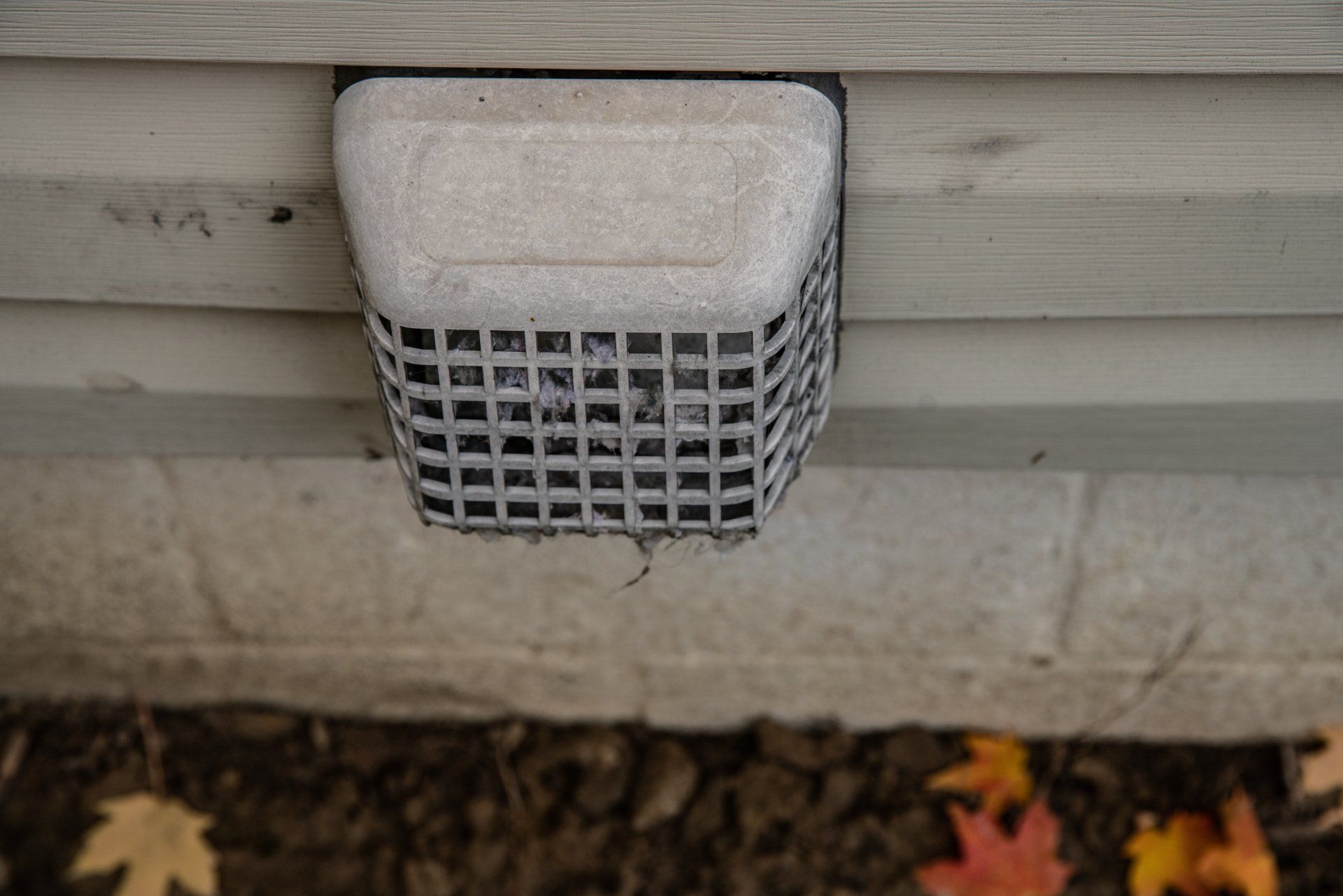 A close-up view of a dryer vent covered in lint and debris, indicating the need for cleaning.