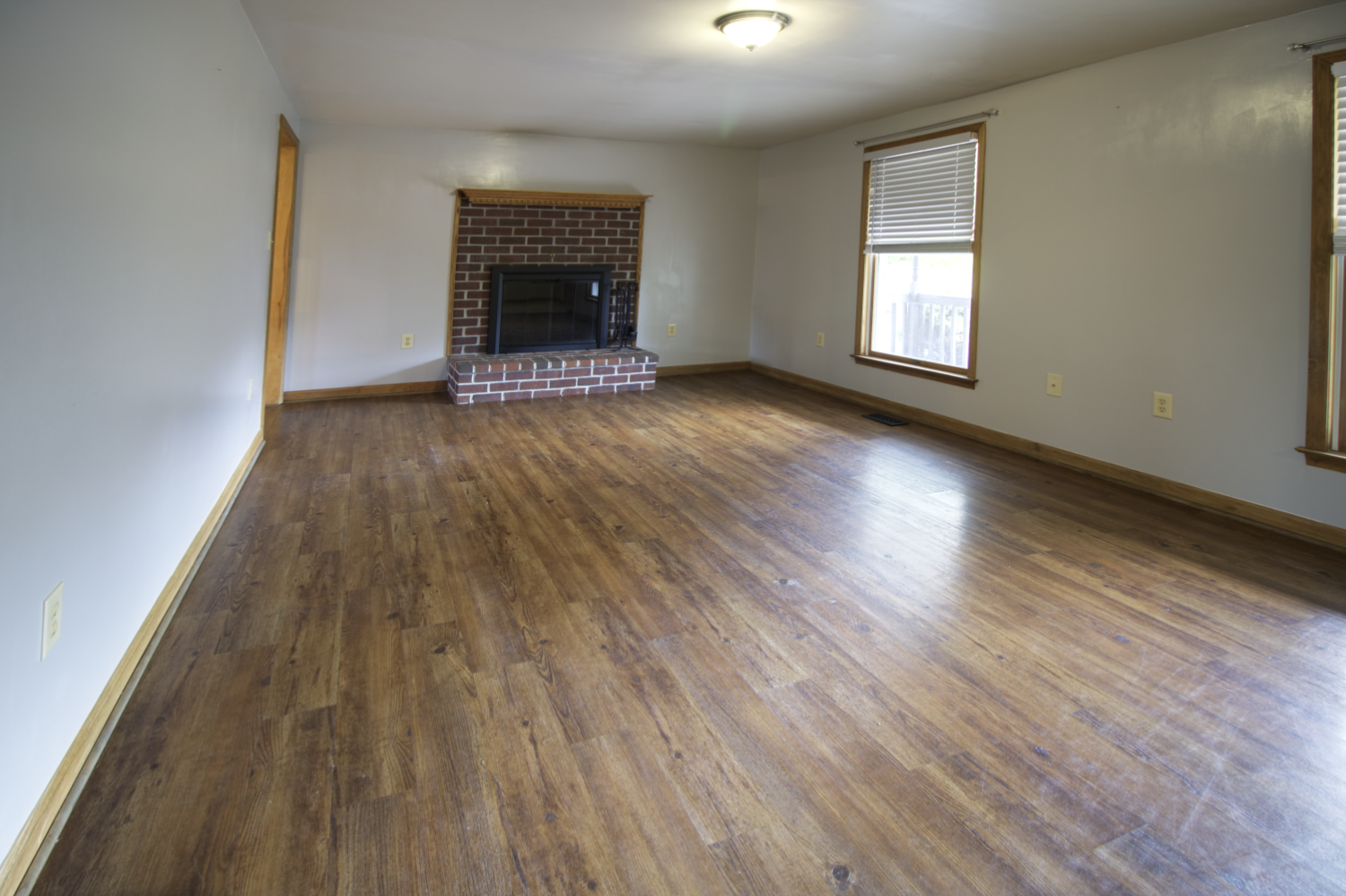An empty living room with hardwood floors and a fireplace.
