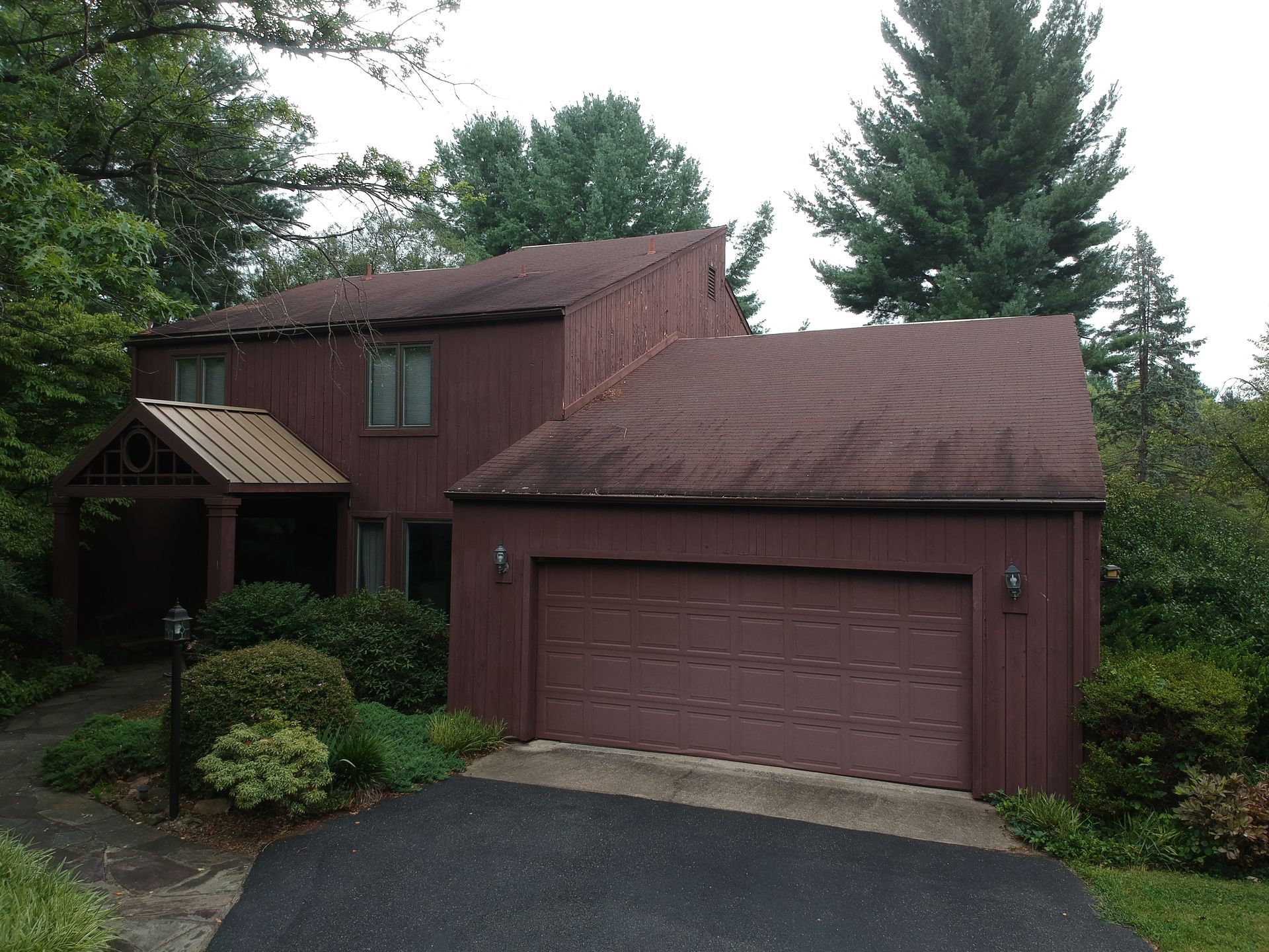 A house with a red garage door is surrounded by trees