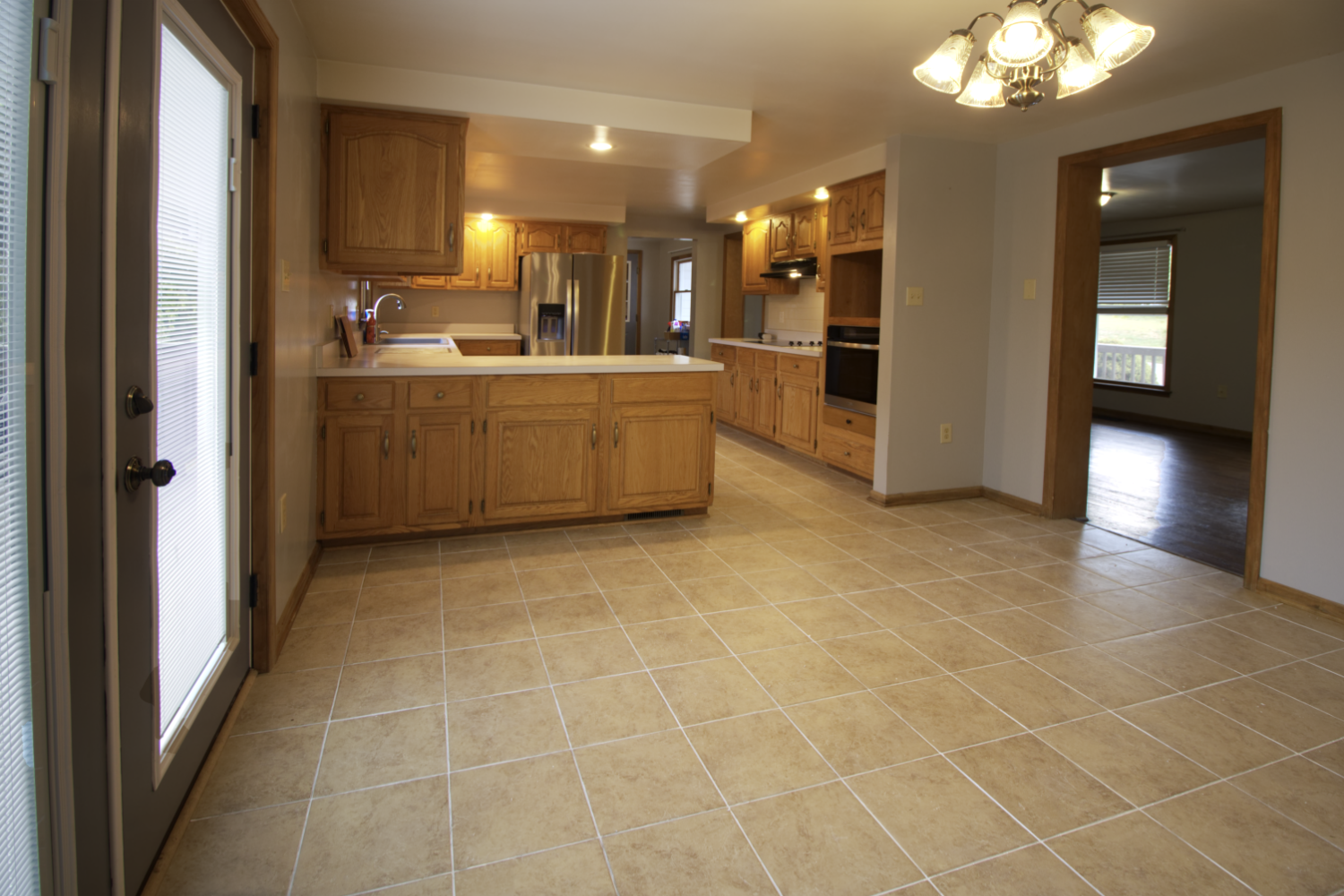 An empty kitchen with tile floors and wooden cabinets