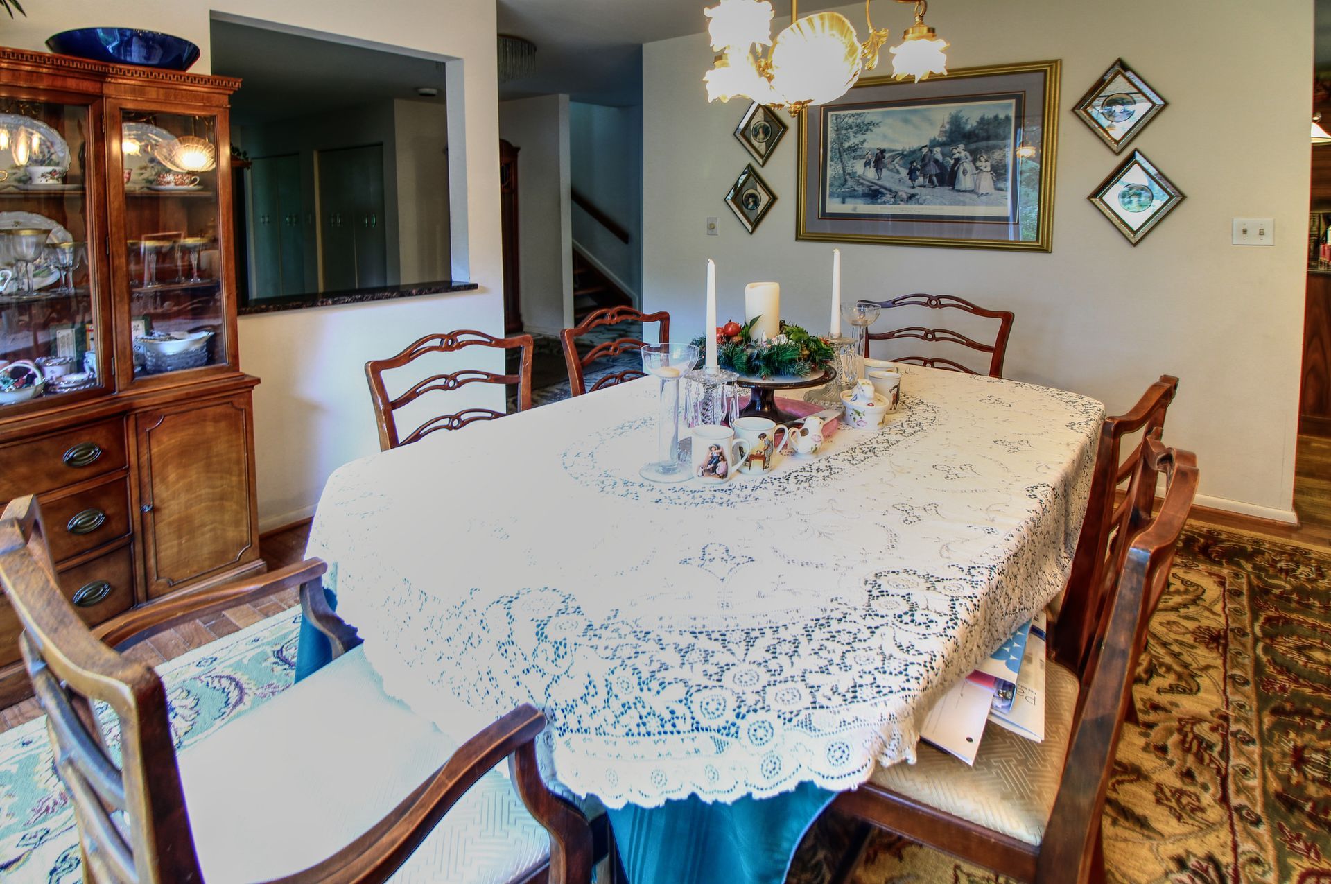 A dining room table with a lace tablecloth and chairs