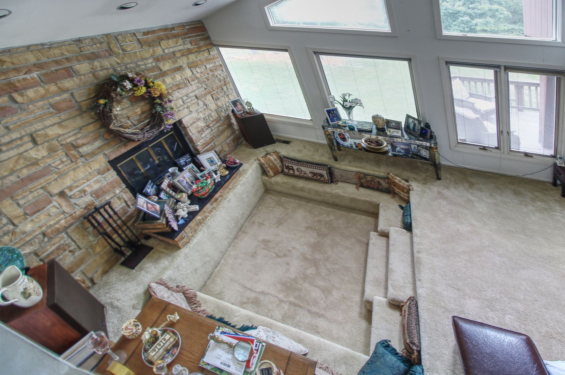 An aerial view of a living room with a fireplace and stairs.