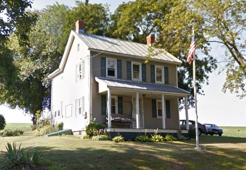 A house with a porch and an american flag in front of it