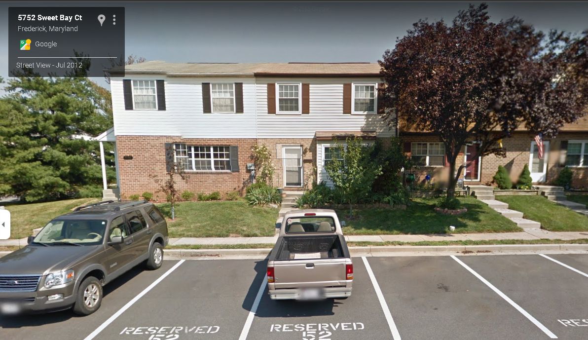 A truck is parked in a parking lot in front of a house.