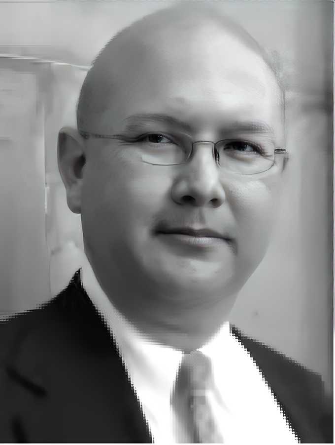 A bald man wearing glasses and a suit and tie