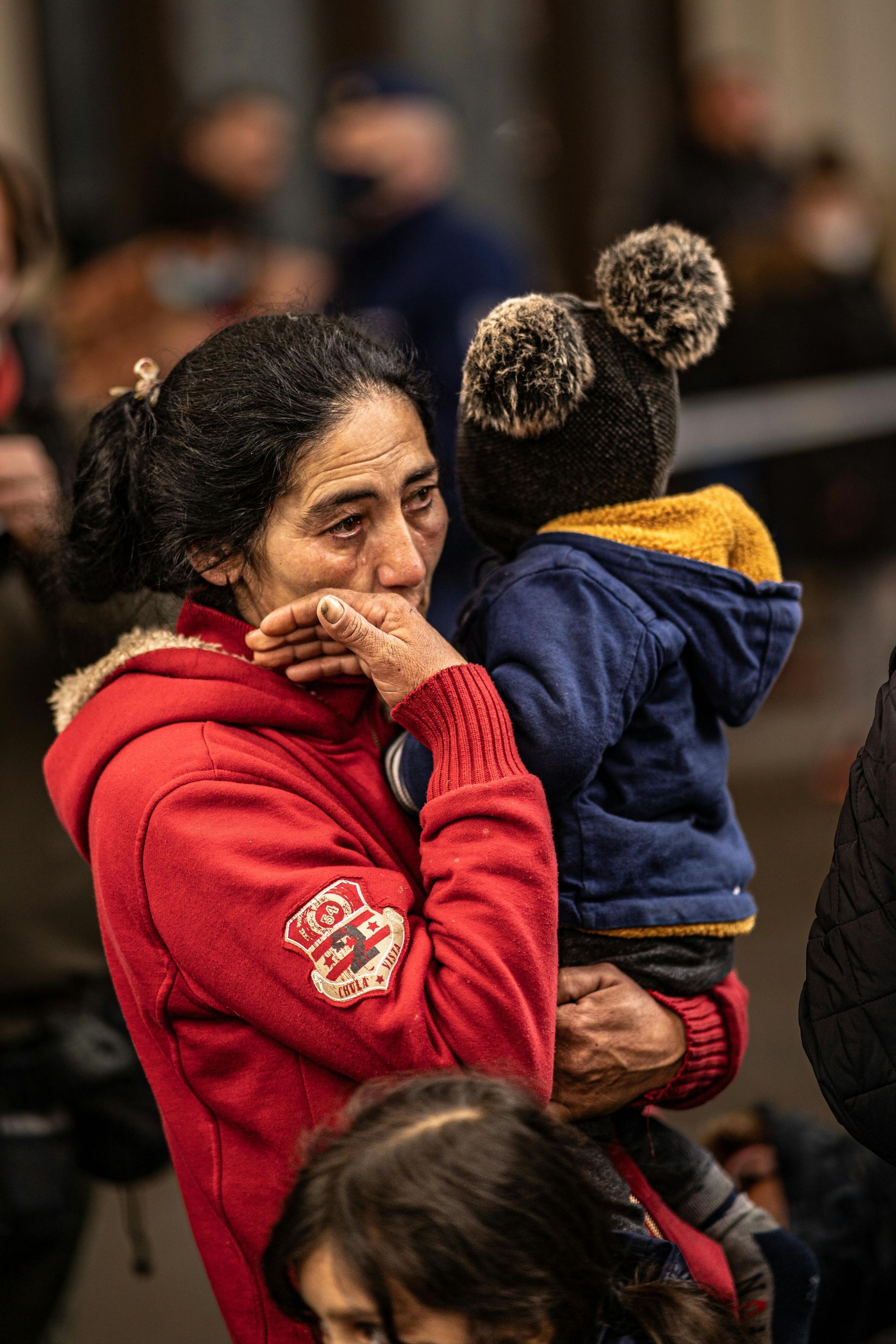 A woman is holding a child in her arms and crying.