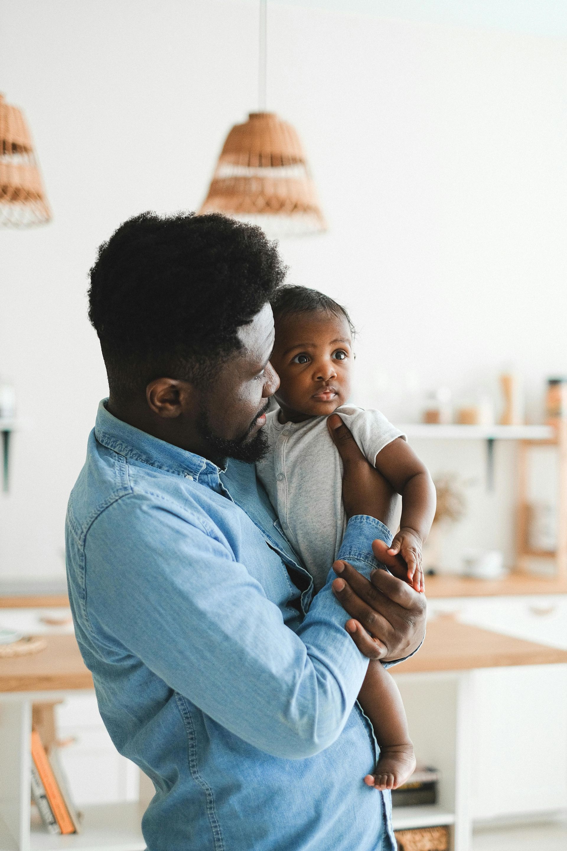 A man is holding a baby in his arms in a kitchen.