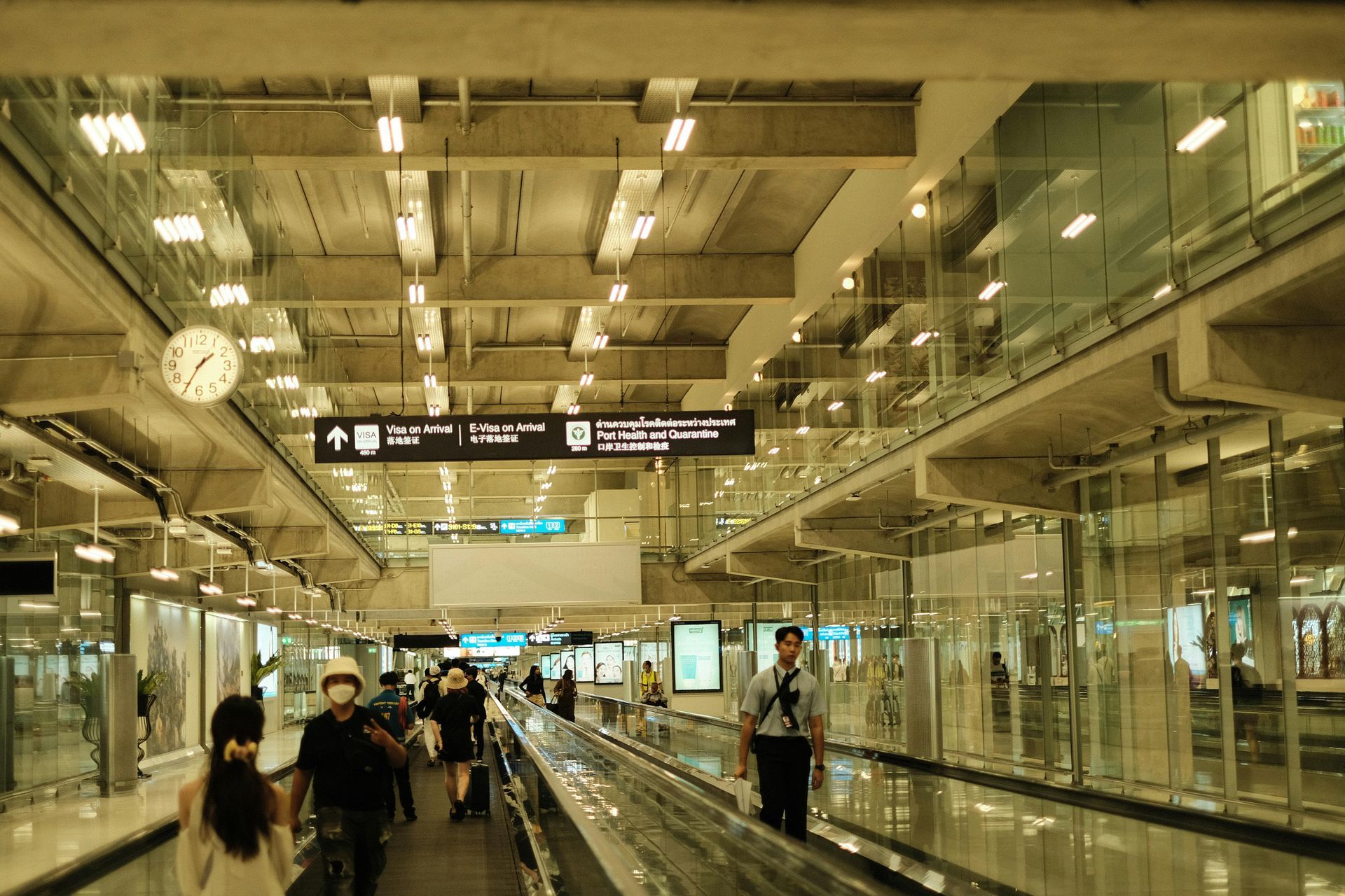 A group of people are walking down an escalator at an airport.