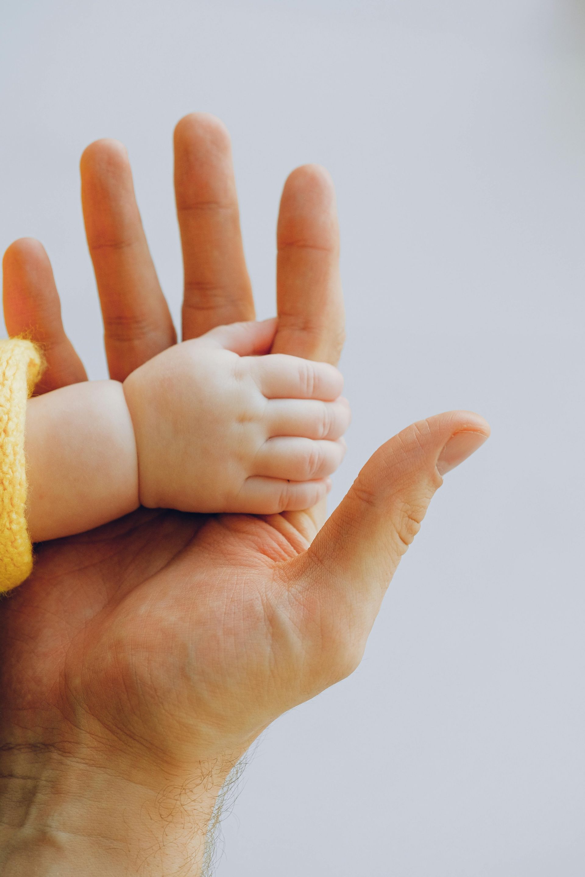 A man is holding a baby 's hand in his hand.