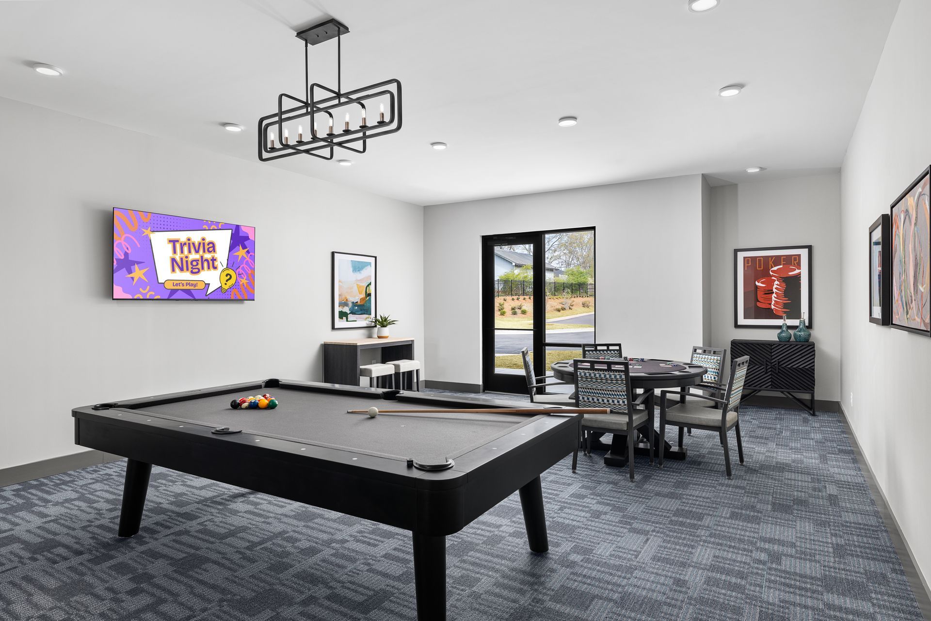Spacious game room with a pool table, wall-mounted TV, seating area, and glass doors to outside.