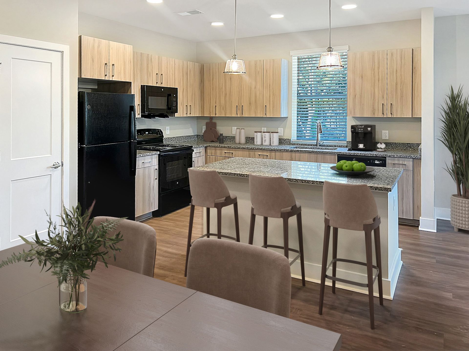 Modern apartment kitchen with granite counters, an island, and light wood cabinets.