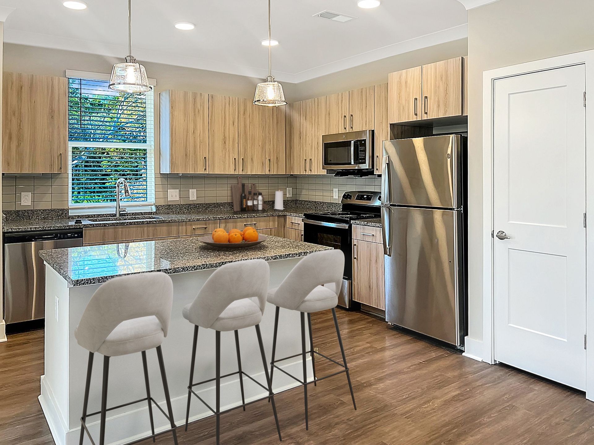 Modern kitchen with granite countertops, stainless steel appliances, and an island with seating.